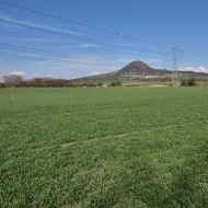 Cesta po zelené podél pole s výhledem na Oblík